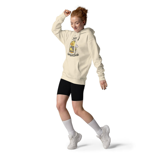 A woman wearing a beige hoodie with a duck character and text CERTIFIED BUMBLEDUCK, black shorts, white socks, and white sneakers on a white background.