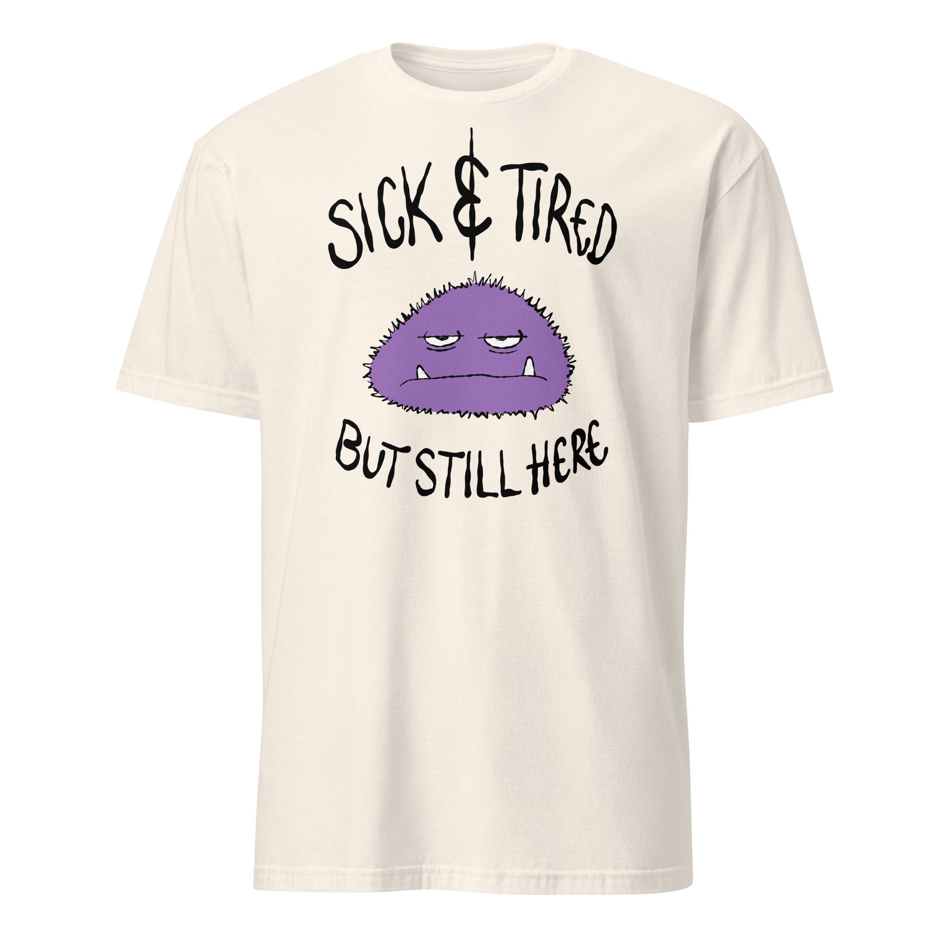 Beige t-shirt with a purple cartoon character and text sick and tired but still here on a white background