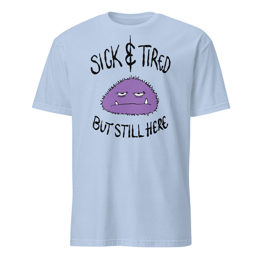 Light blue t-shirt with a purple cartoon character and text sick and tired but still here on a white background