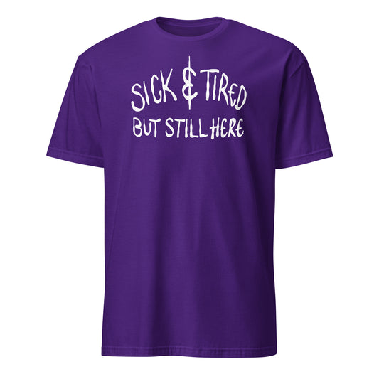 Purple t-shirt with white text 'SICK & TIRED BUT STILL HERE' on a white background