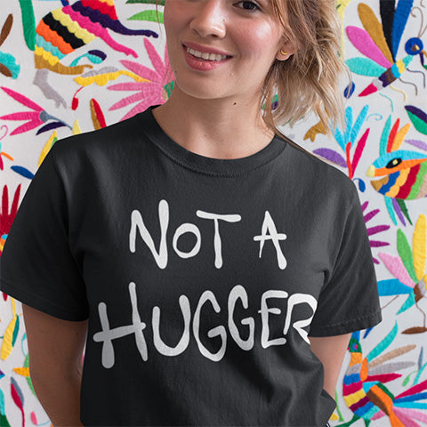 Person wearing a black t-shirt with 'NOT A HUGGER' text in front of a colorful abstract background